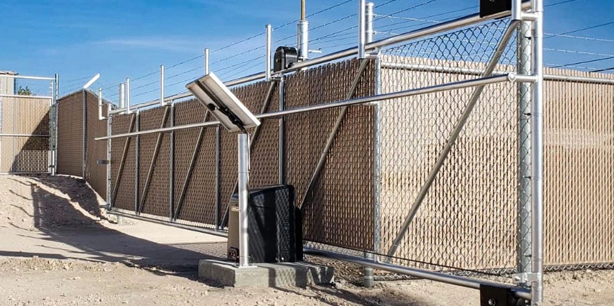 A secured metal gate with barbed wire under a clear blue sky.