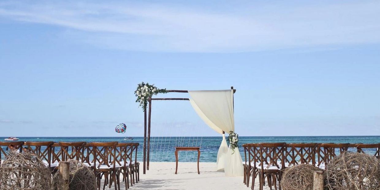 Beach wedding setup with chairs and floral arch facing the ocean.