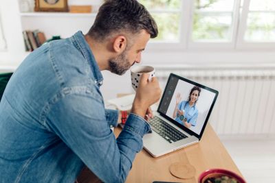 Man video chatting with woman on laptop.