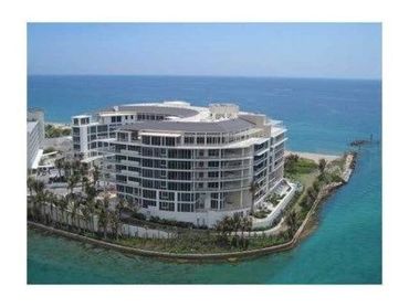 Modern waterfront building surrounded by water with ocean in background.