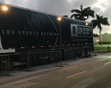 CBS Sports Network trailer parked near palm trees during dusk.