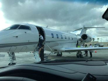 Passengers boarding a private jet on a cloudy day.