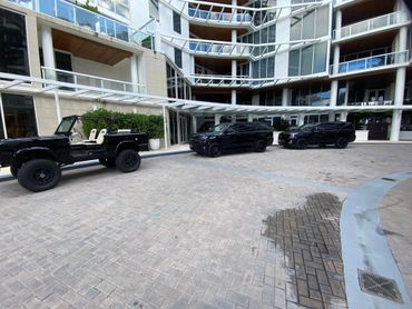 Three black SUVs parked outside a modern building with large glass windows.