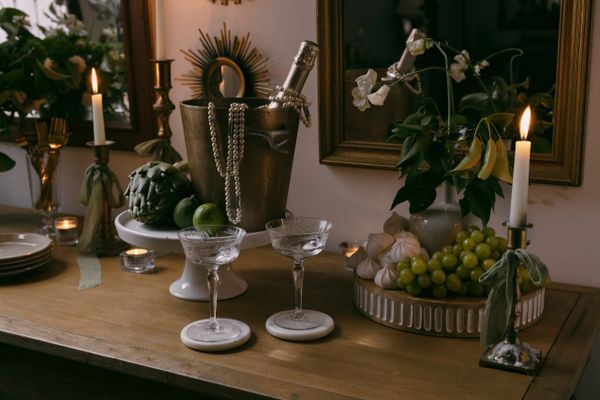 Elegantly styled buffet with champagne in an ice bucket, glasses, fruit, flowers, and lit candles
