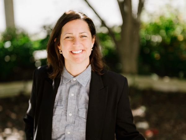 Smiling woman in a blazer outdoors.
