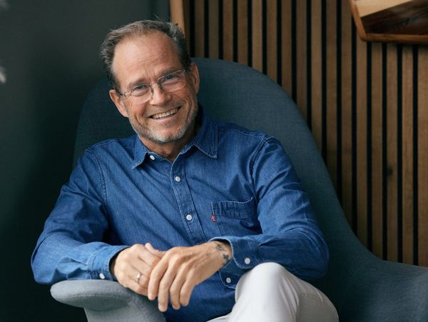 Smiling man wearing glasses and a denim shirt.