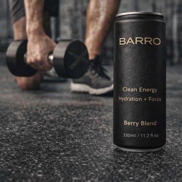 A can of BARRO energy drink with a person holding a dumbbell in the background.