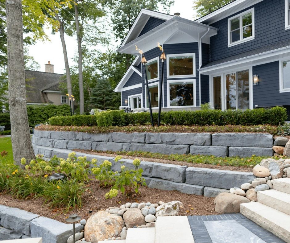 Modern blue house with stone terraces and garden.