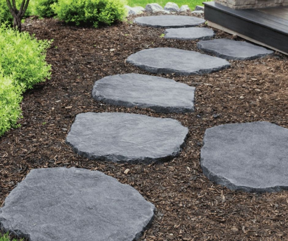 Stone path with mulch and greenery beside a porch.