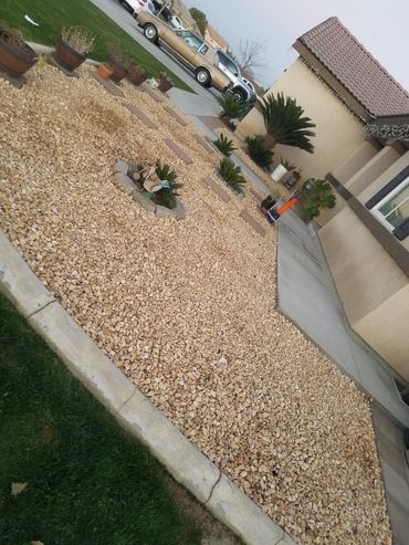 Jardín delantero con piedras decorativas y plantas.