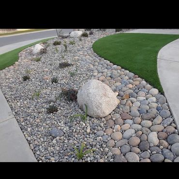 Jardín decorativo con rocas y césped artificial.