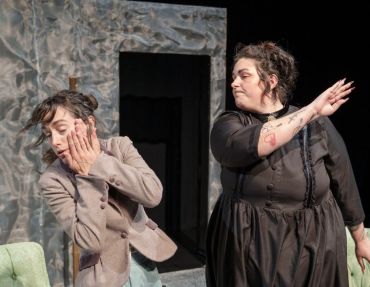A woman slaps another woman during a theatrical performance.