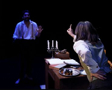 Two actors in an intense theatrical scene with dramatic lighting.