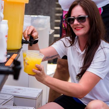 a woman with red lipstick pouring mimosas in the souvenir cups from the festival