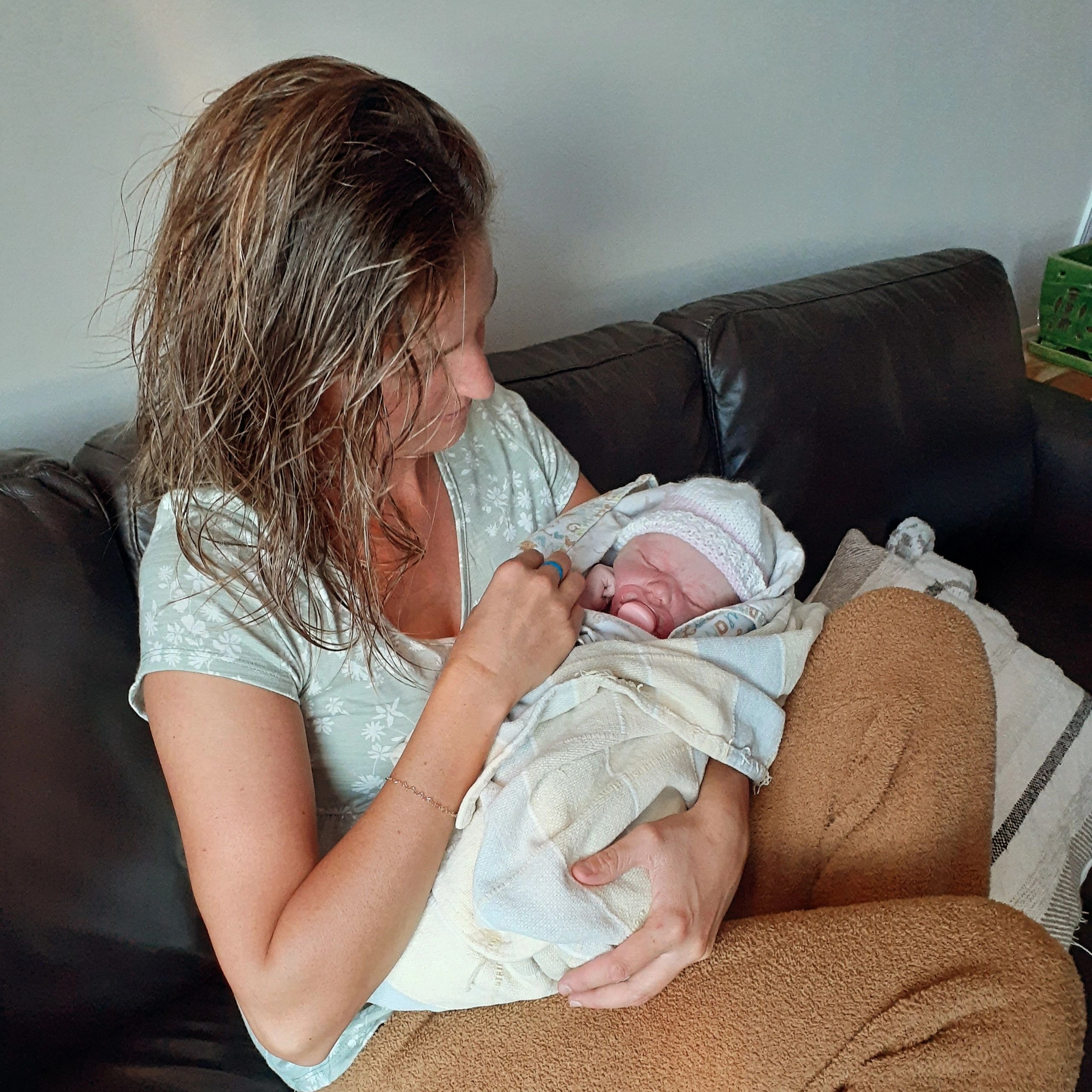 Woman lovingly holding a sleeping baby wrapped in a blanket.