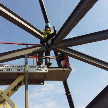 Construction worker giving thumbs up on steel framework platform.