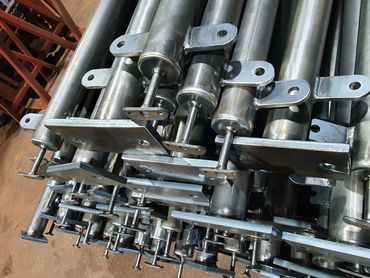 Stack of metal industrial components with cylindrical rods and mounting plates.