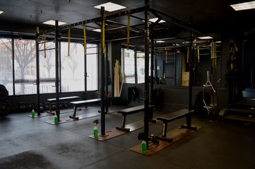 Imagen de estantes y banco, cuerdas de resistencia, platos de pesas.