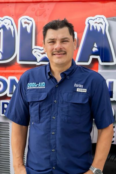 Picture of the CEO, Carlos Rivera posing on the side of his truck. You see his logo behind him.
