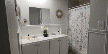 Bright bathroom with white vanity and decorative shower curtain.