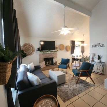 Cozy living room with blue chairs and a TV above the fireplace.