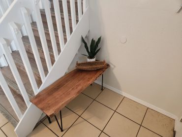 Wooden bench with plant and basket under staircase.
