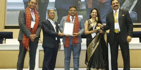 Group of five people at an award ceremony, holding a certificate and trophy.