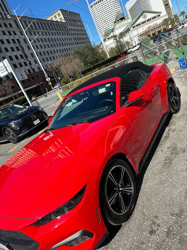 Red convertible sports car parked in a city lot.