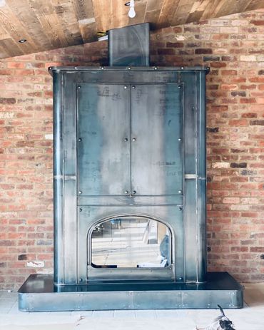 Industrial-style metal fireplace against a brick wall with a dog nearby.