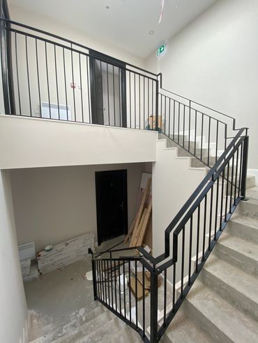 Indoor staircase with black railing and construction materials scattered.