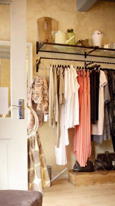 Cozy boutique corner with hanging clothes and decorative items on a shelf.