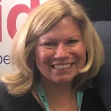Smiling blonde woman with a lanyard.