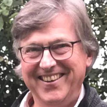 Smiling man with glasses outdoors.