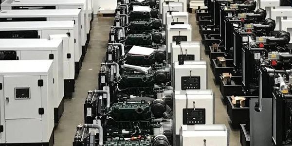 Rows of industrial generators lined up in a warehouse.