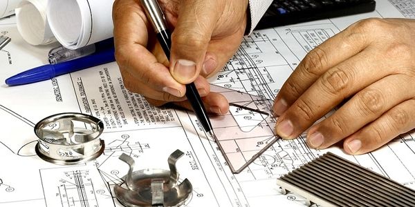 An engineer drafting technical drawings with tools.