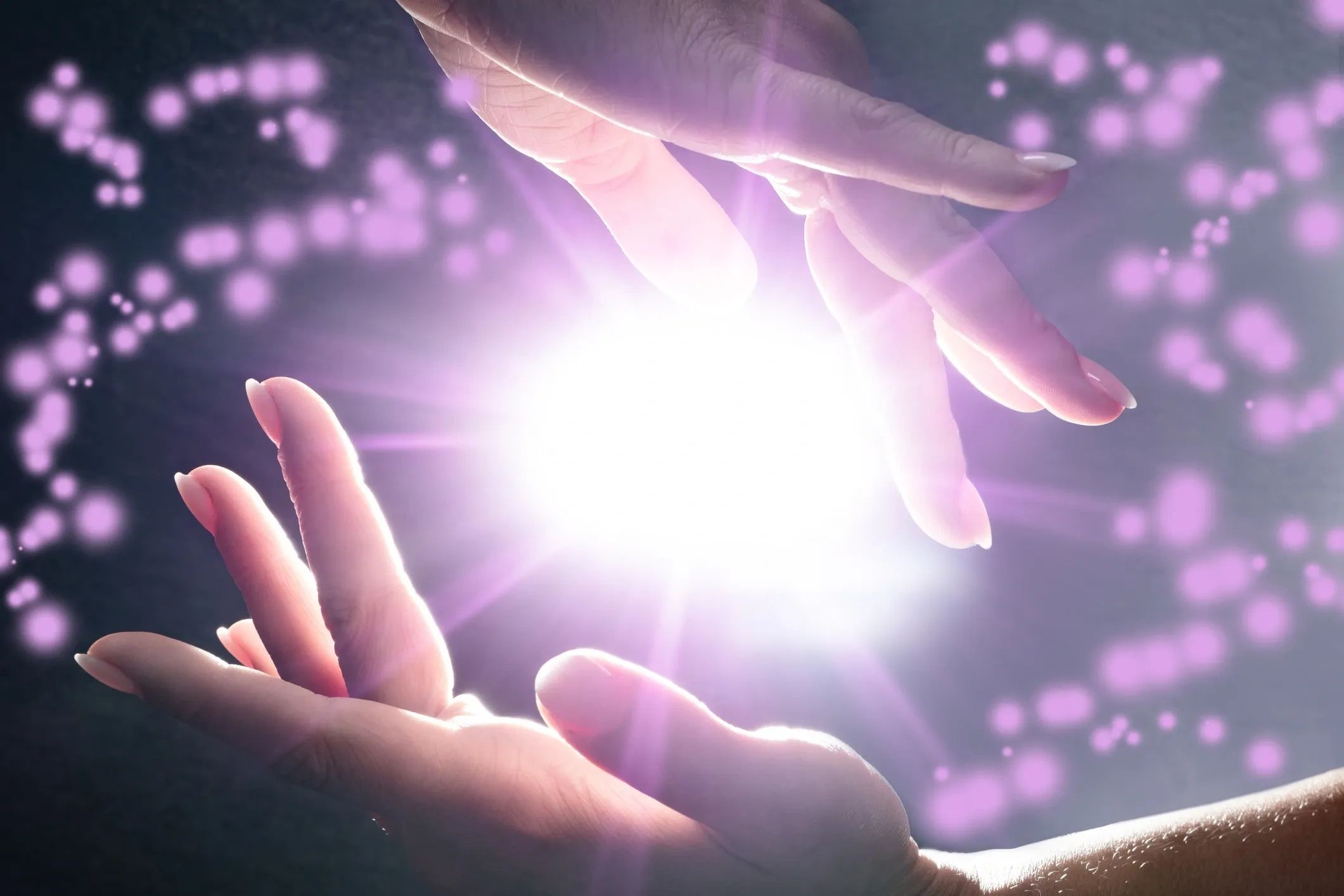 Hands holding a glowing orb with purple light particles around.