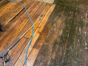 Wooden deck being cleaned by pressure washing, showing a clear before and after.