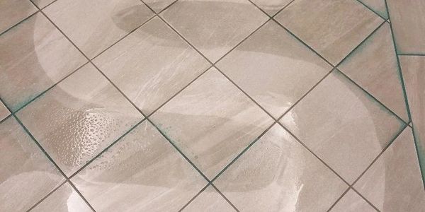 A floor cleaning machine polishing tiled floor, leaving a shiny reflection.