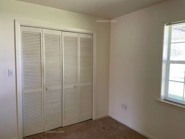 Looking at white closed louver doors on a closet, with window