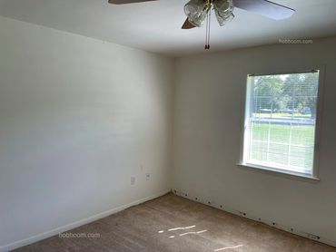 View of an empty bedroom with window and ceiling fan.