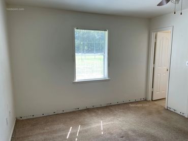 looking in empty bedroom with window and bathroom door.