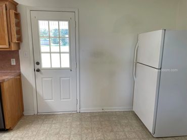 A view of a refrigerator sitting near kitchen cabinets.