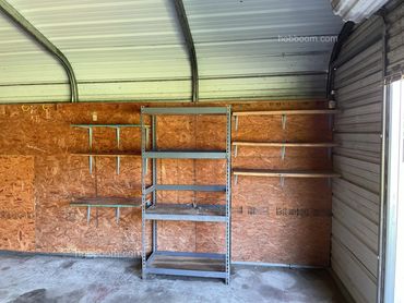 Looking at metal shelves built against a chipboard wall.