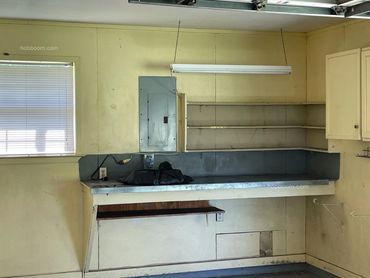 A view of a workbench, window, breaker box and lights in an empty garage.