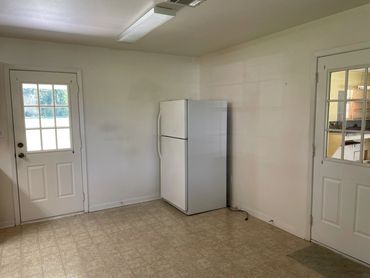A refrigerator in the corner of a room showing two doors.