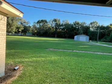 Looking toward an outbuilding from the corner of a brick house.