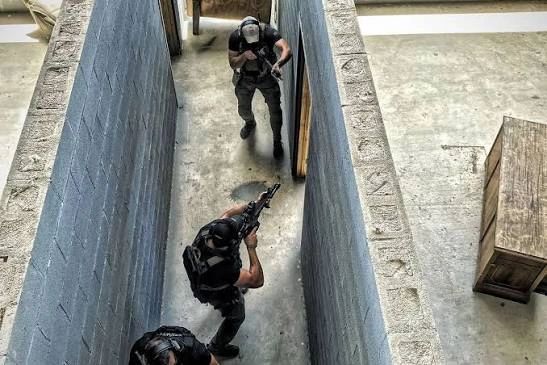 Three armed men in a narrow corridor during a training.