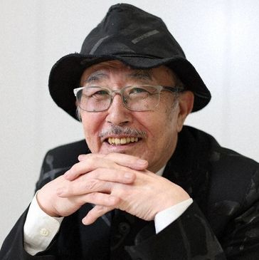 Smiling elderly man wearing glasses and a black hat.