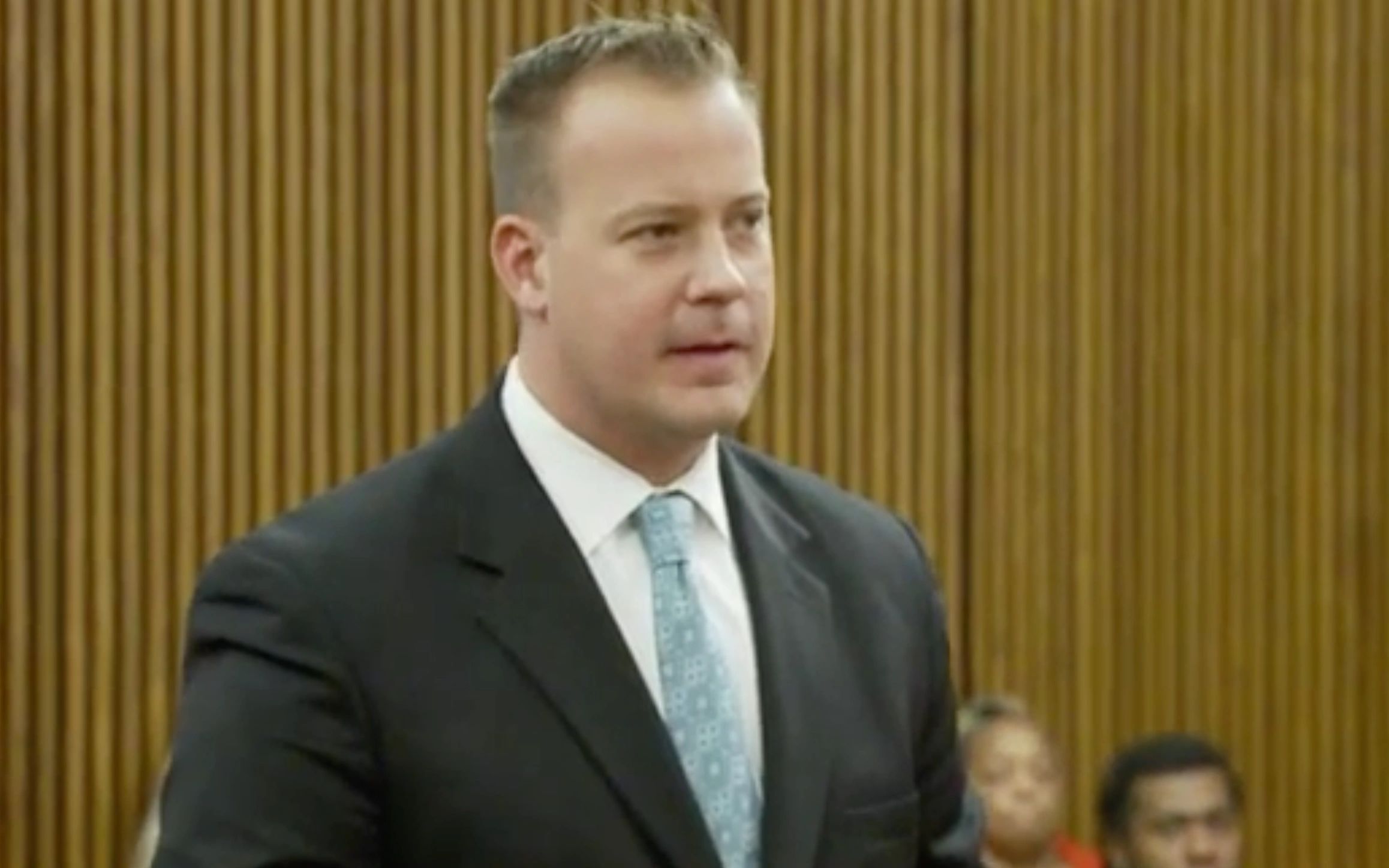 Man in a suit speaking in a courtroom.