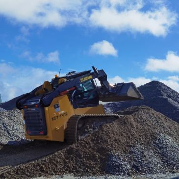Yellow bulldozer moving gravel under blue sky.